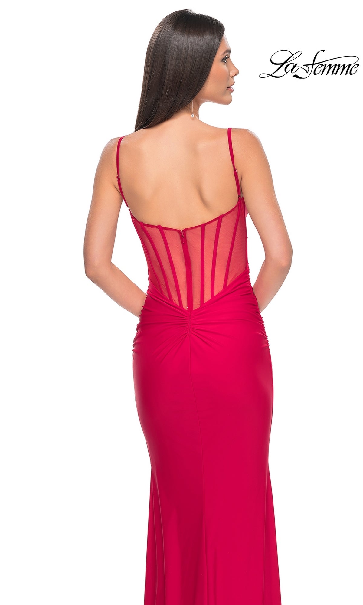 A woman models the La Femme Sheer-Back Long Jersey Prom Dress 32153 in fitted bright red with thin straps and a corset-style sheer back, posed against a white background. The